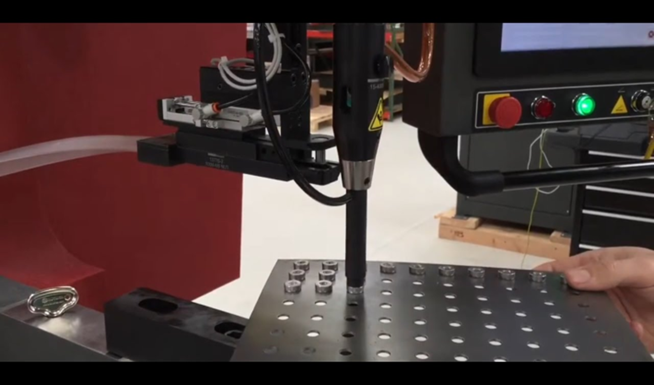 Machine drilling holes in metal sheet.